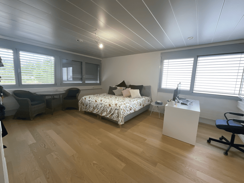 Bedroom with bed, desk, chair, and windows with blinds