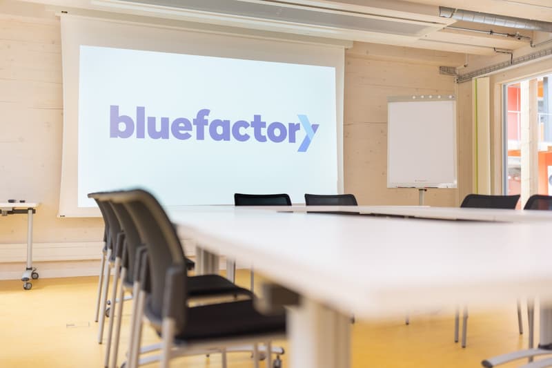 conference room with table, chairs, screen, whiteboard, wooden wall