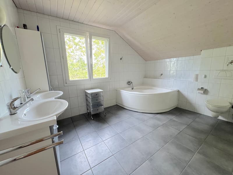Salle de bain avec baignoire d'angle et double vasque.