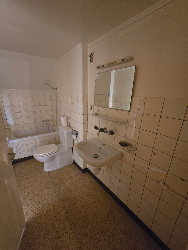 Tiled bathroom with toilet, sink, and bathtub. Washing machine is visible.