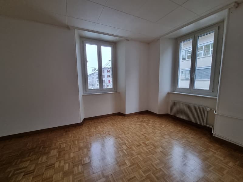 empty room, hardwood floor, white walls, two windows, heating radiator