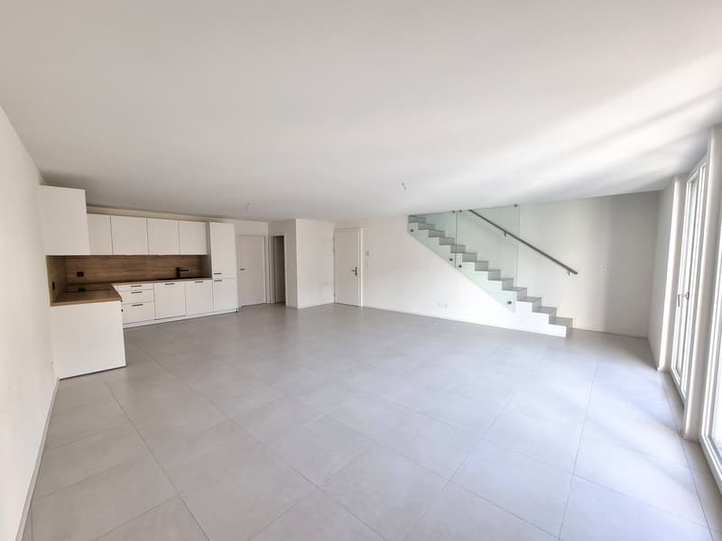 Open-plan kitchen with cabinets, tile flooring, glass staircase.