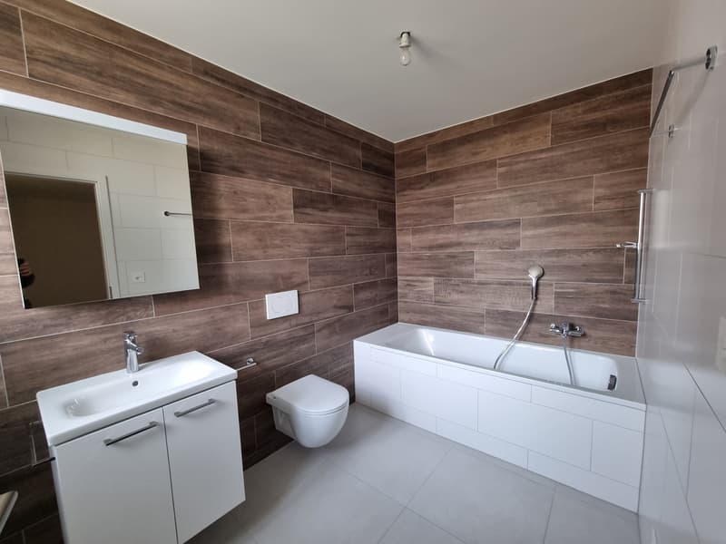Bathroom: white ceramic tiles, white bathtub, white toilet, white vanity, wall-mounted mirror