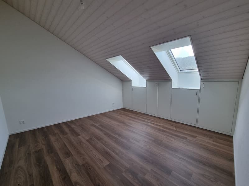 empty room with wooden floors, white walls, two windows in ceiling, no furniture