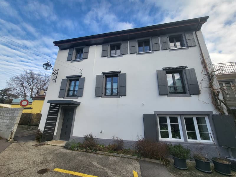 White-painted three-story house, grey-shutter windows, black front door, parking in front, street lamp.