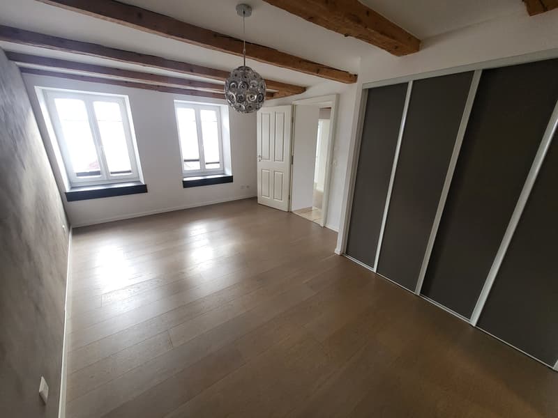 empty room with wooden floor, exposed wooden ceiling, large windows, sliding closet