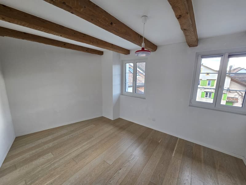 empty room, wooden floor, white walls, wooden beams, two windows, view of the outside