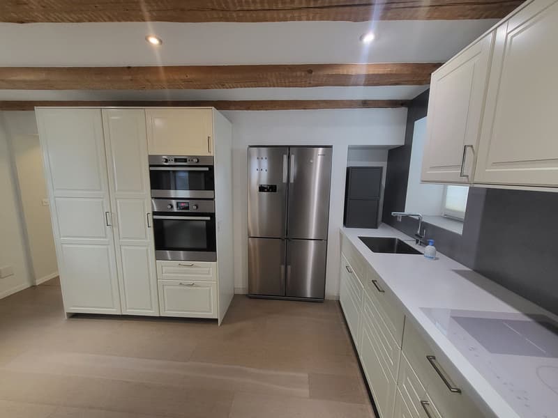 modern kitchen with white cabinetry, stainless steel appliances, wooden beams, tiled flooring