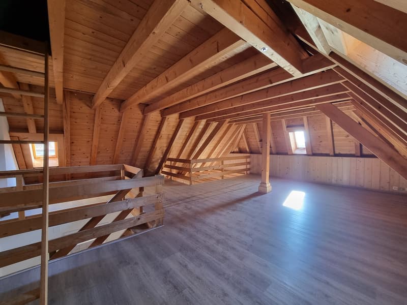 empty attic room with wooden beams, wooden floor, wooden railings, windows