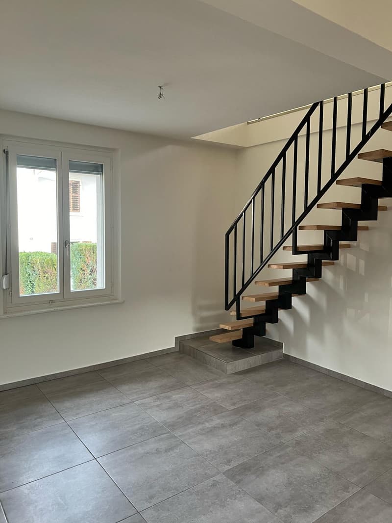 Modern staircase with wooden steps and black handrails. Tiled floor. Window to the side. Minimalist design.