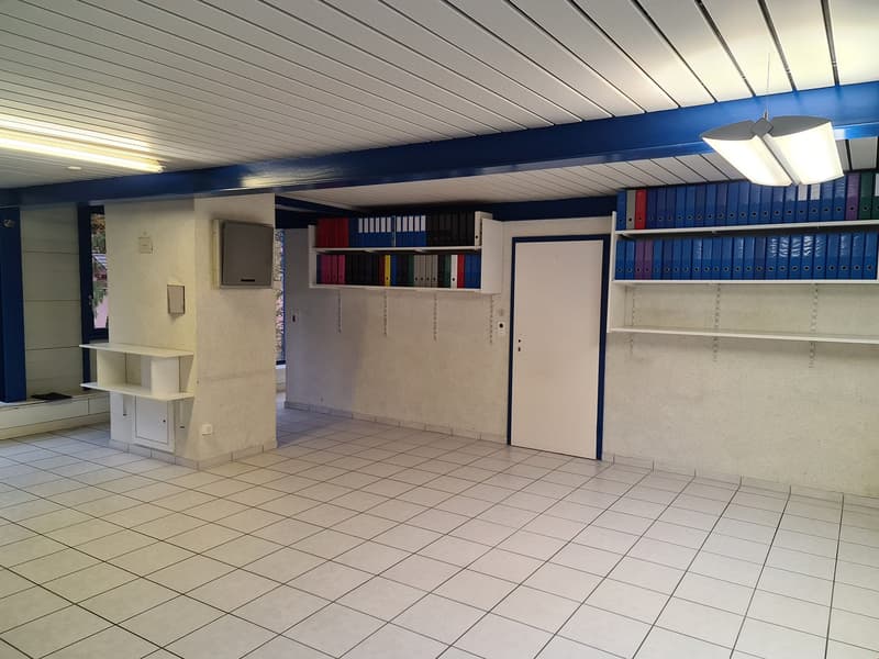 Empty room, white tiles, white walls, two rows of shelves with files, fluorescent ceiling lights