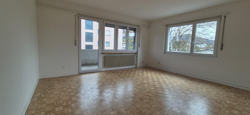 Empty room, wooden floor, large windows, doors, balcony