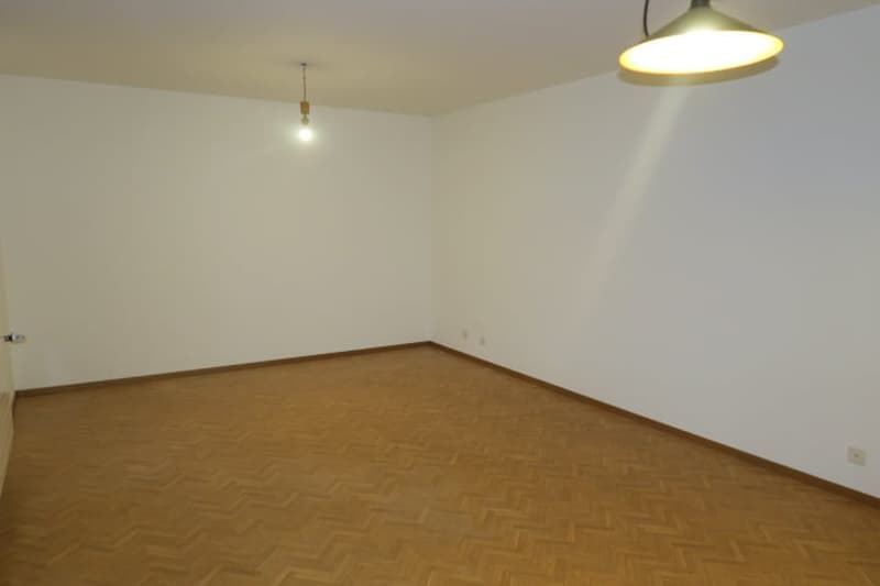 empty room with wooden floor, white walls, ceiling light, electrical outlets