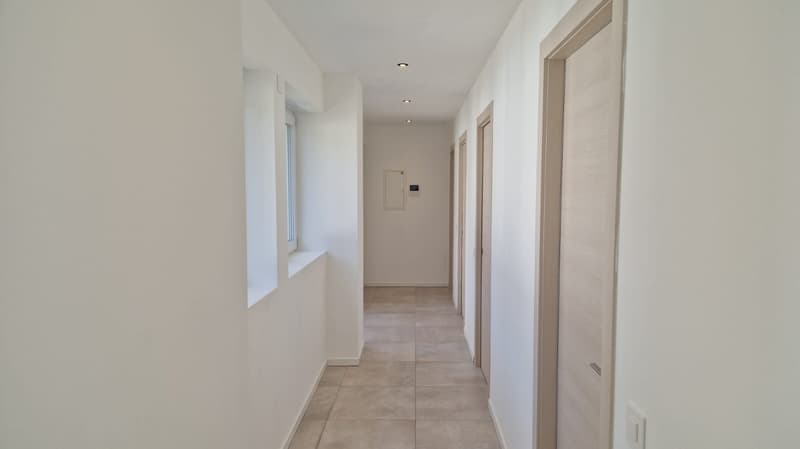 tiled floor, white walls, a single window, illuminated by ceiling lights