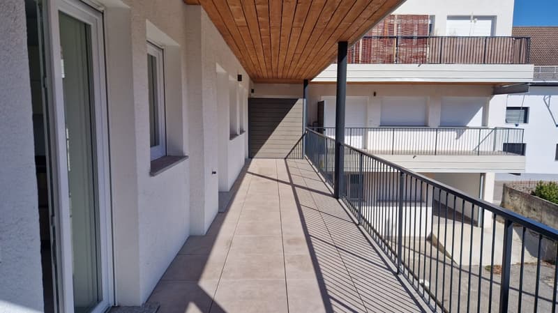 A balcony with tiled floor and a black railing, attached to a building