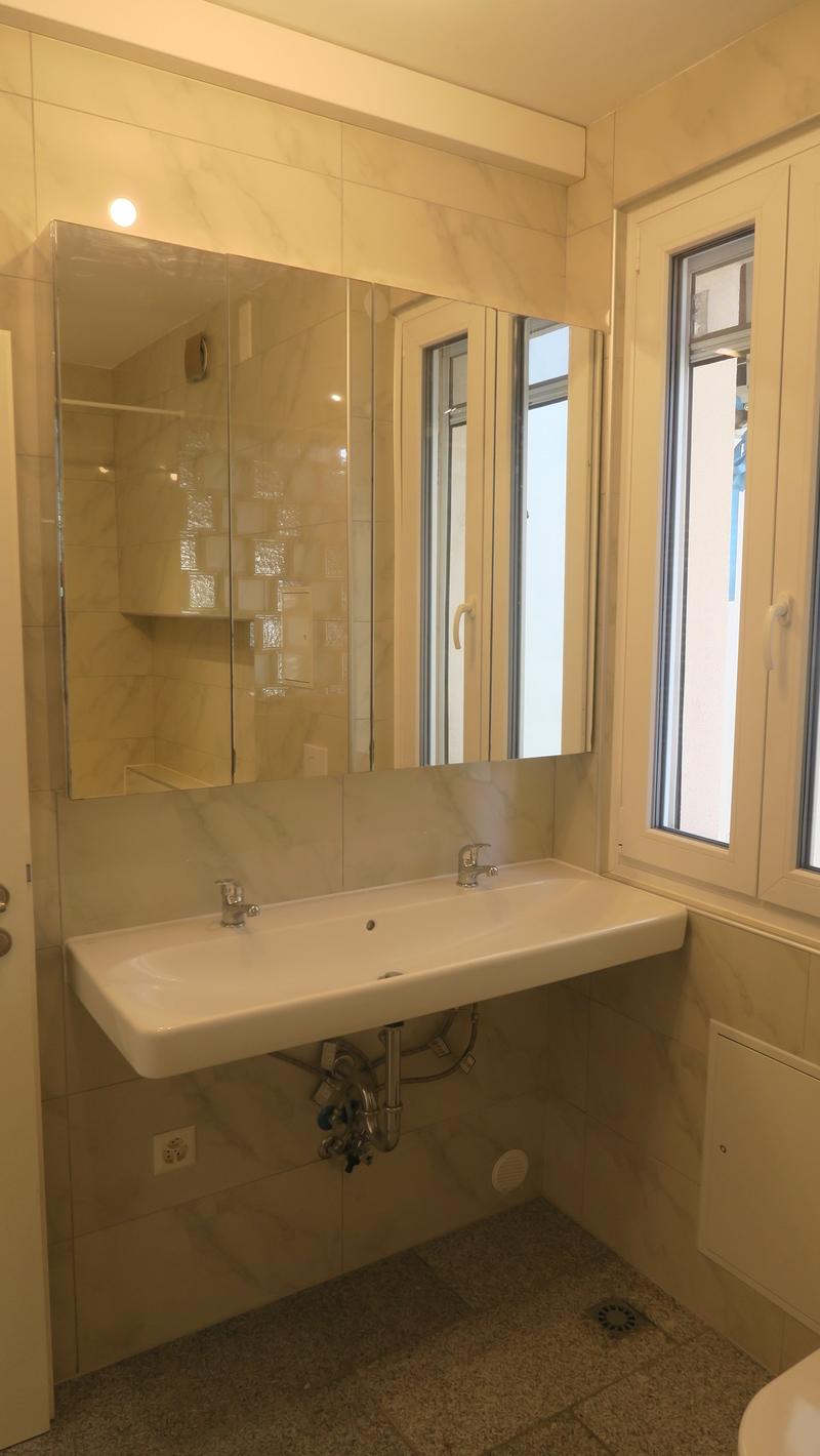 Bathroom with a white sink, mirror, and tiled walls