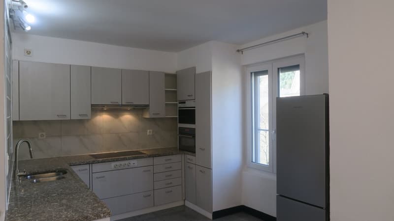modern kitchen with granite countertop, stainless steel sink, built-in oven, dishwasher, refrigerator, white cabinets, power outlets, and a window