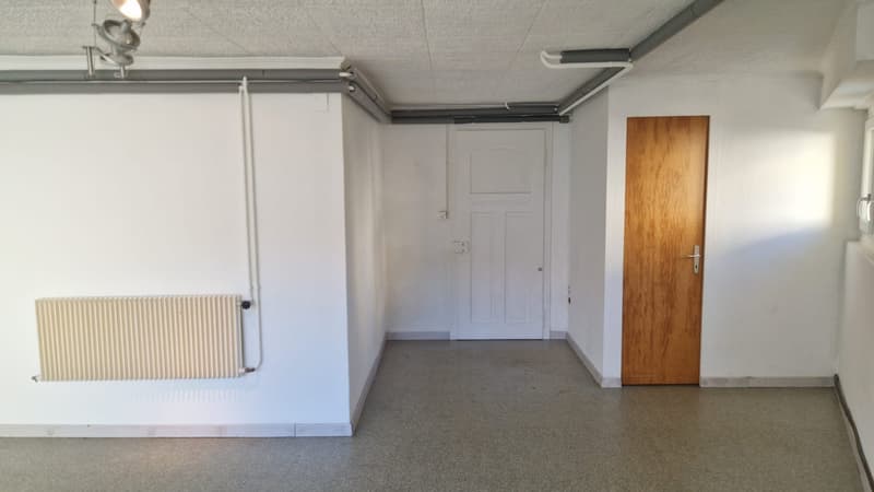 Empty room with white walls, wooden door, white door, radiator, ceiling lights