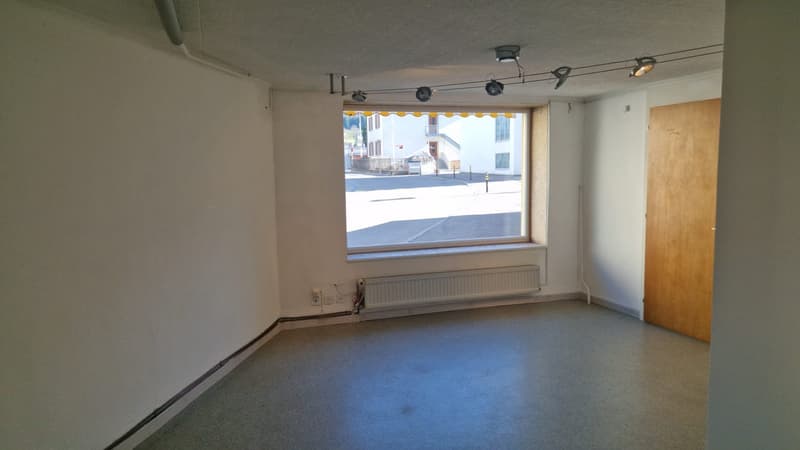 empty room, white walls, gray floor, large window, radiator, power outlets