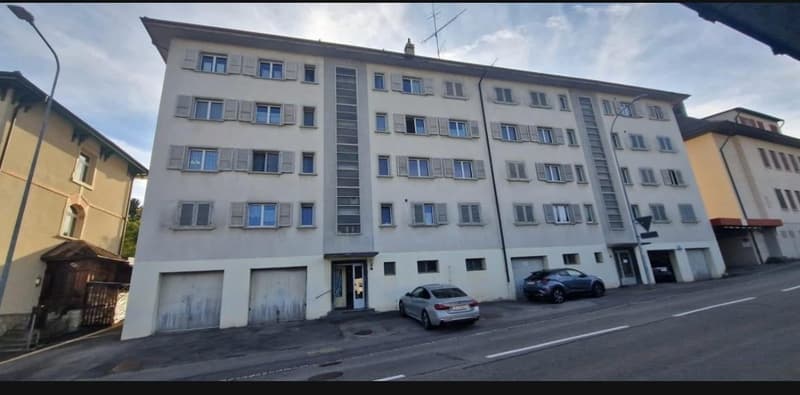 5 story building, white exterior, multiple windows, 2 garages, 2 cars parked