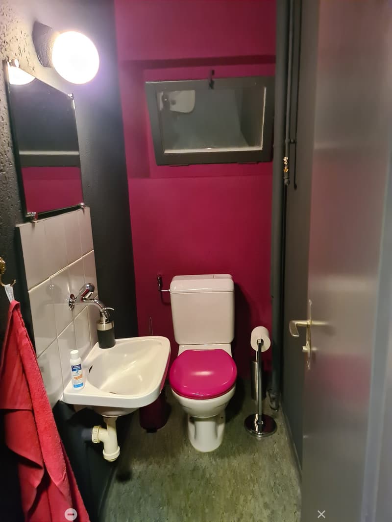 A small bathroom with a toilet, sink, and mirror.