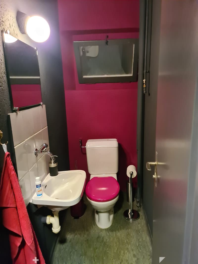 A small bathroom with a toilet, sink, and mirror.
