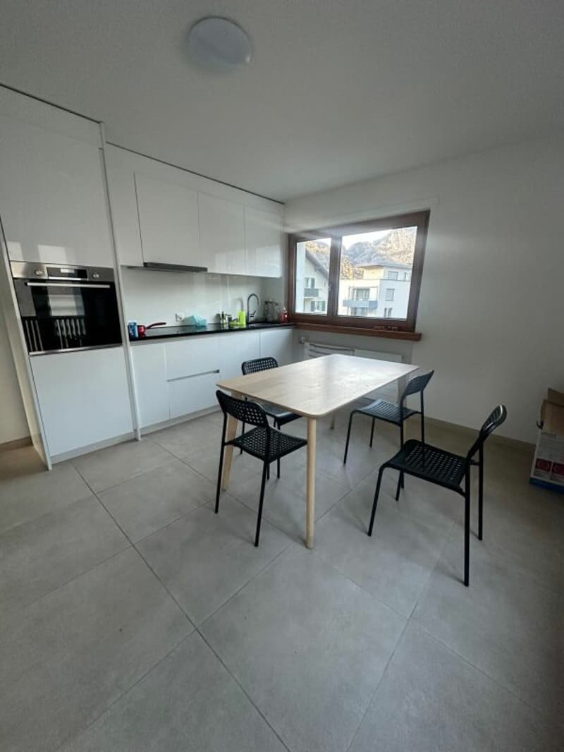 modern kitchen with white cabinets, wooden dining table, black chairs, oven, sink, window with view