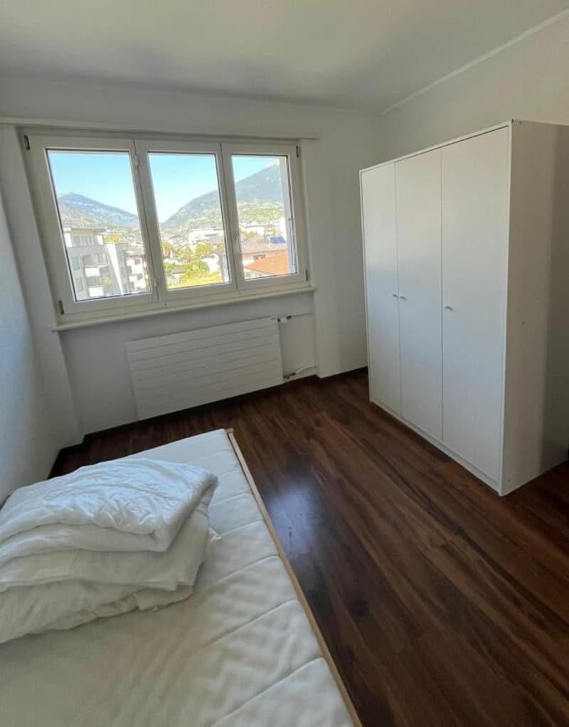bedroom with bed, white wardrobe, wooden floor, large window with view