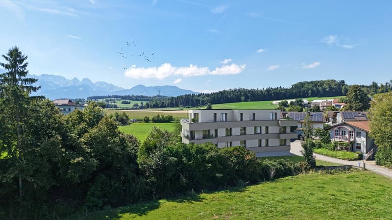 Apartment building with 5 floors, multiple solar panels, surrounded by green fields and trees