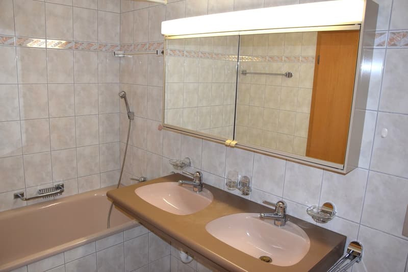 Bathroom with bathtub, double sink, mirror, and shower head