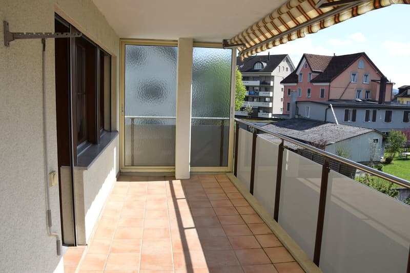 Balcony with tiled floor, glass doors, metal railings, and a view of the neighborhood