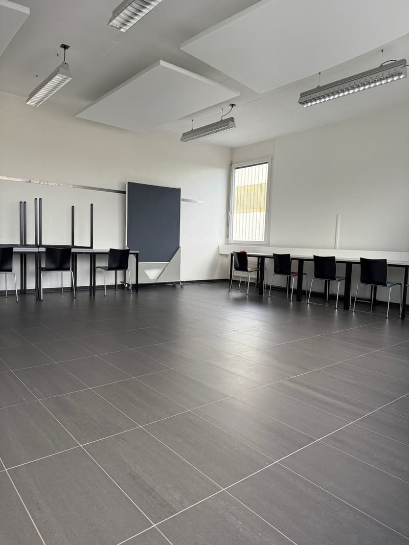 empty room, large tiled floor, large whiteboard, tables and chairs, overhead fluorescent lights