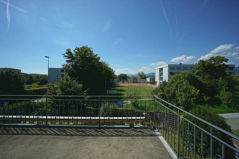 elevated outdoor space, metal railings, tennis court, greenery