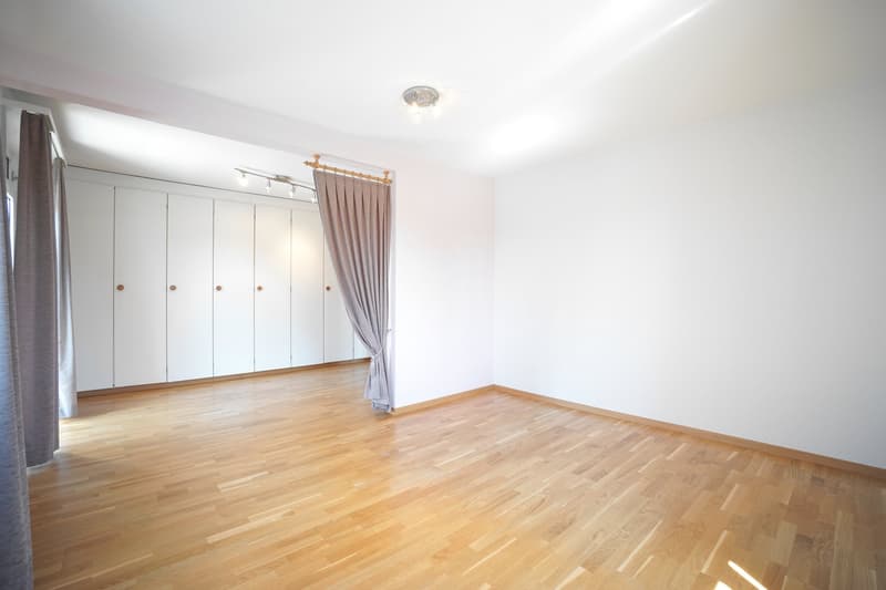 empty room, white walls, wooden floor, ceiling lights, curtained door, multiple wall-mounted cabinets