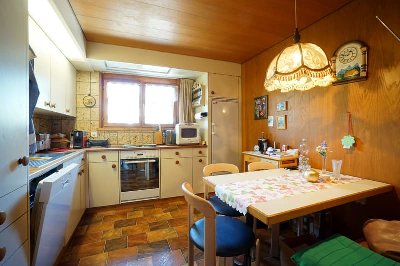 white cabinets, wooden floor, gas stove, oven, microwave, refrigerator, dining table, chairs, hanging lamp, clock, wall decorations, white countertop, sink, faucet