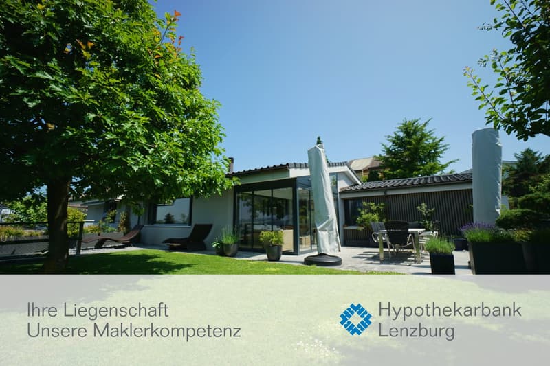 Modern house with glass walls, terrace, garden, and outdoor seating area