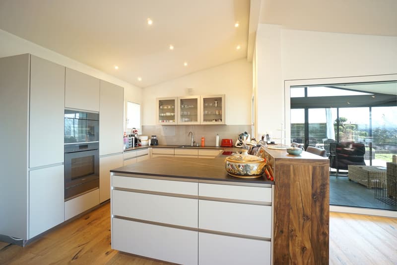 modern kitchen with white cabinets, wooden island, granite countertop, stainless steel appliances, large windows