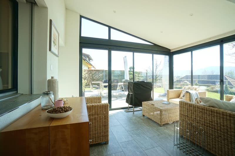 living room with large windows, wicker furniture, bowl of nuts, wooden table, view of the garden