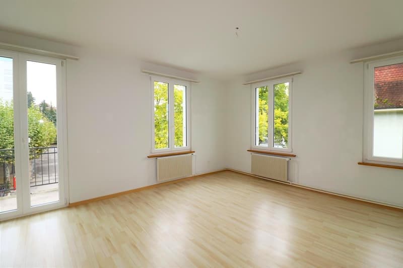 Wooden floor, three windows, sliding doors to balcony, white walls