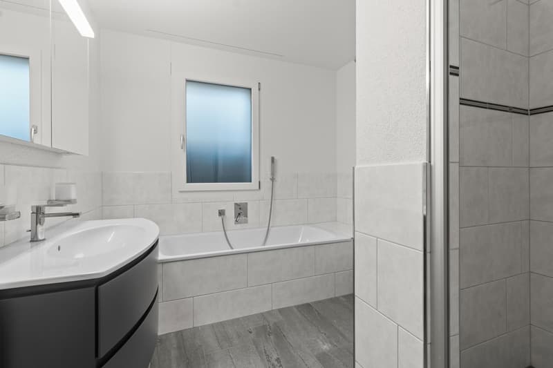 Modern bathroom with white tiles, bathtub, shower stall, sink, and white cabinets