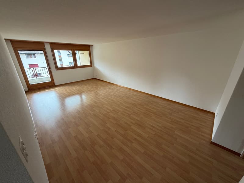 Empty room, hardwood floors, white walls, large windows with balcony, wooden frames