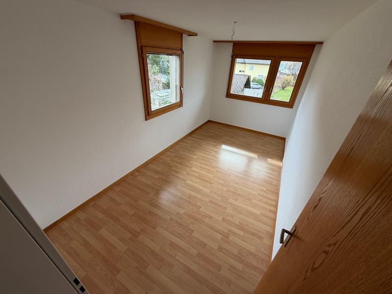 wooden floor, white walls, two windows with wooden shutters, car parked outside, sunlight