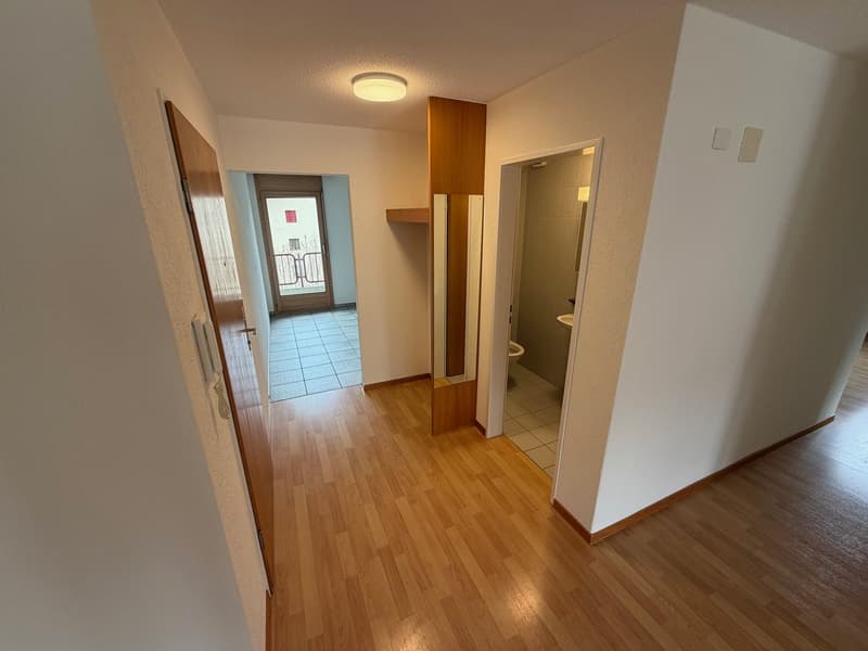 Empty hallway with a bathroom on the right and a door at the end.