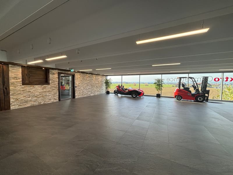 large open space, brick wall, large windows, red forklift, red sports car