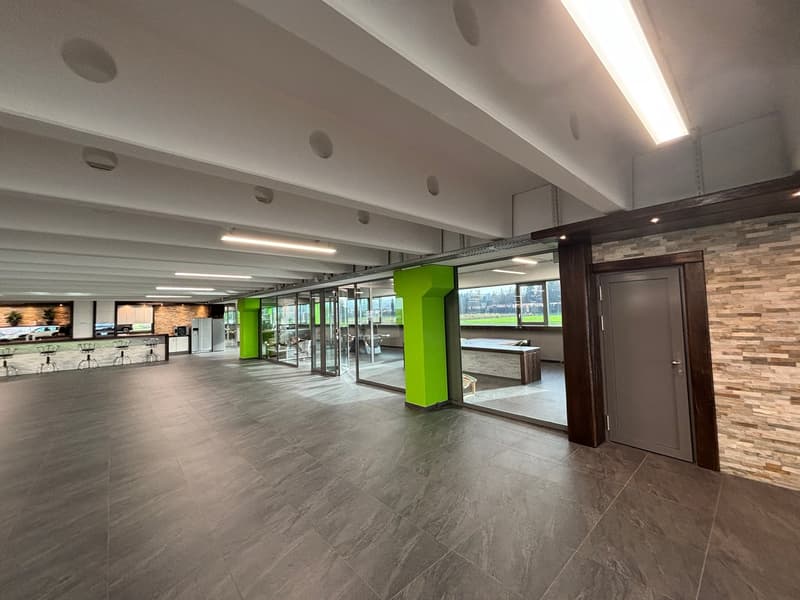 large open space, tiled floor, glass walls, green pillars, ceiling lights