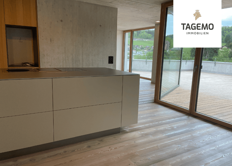 modern kitchen with wooden floor, large island, sliding glass doors to balcony