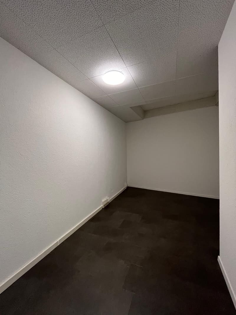 Empty room with white walls, a drop ceiling, and a dark hardwood floor.