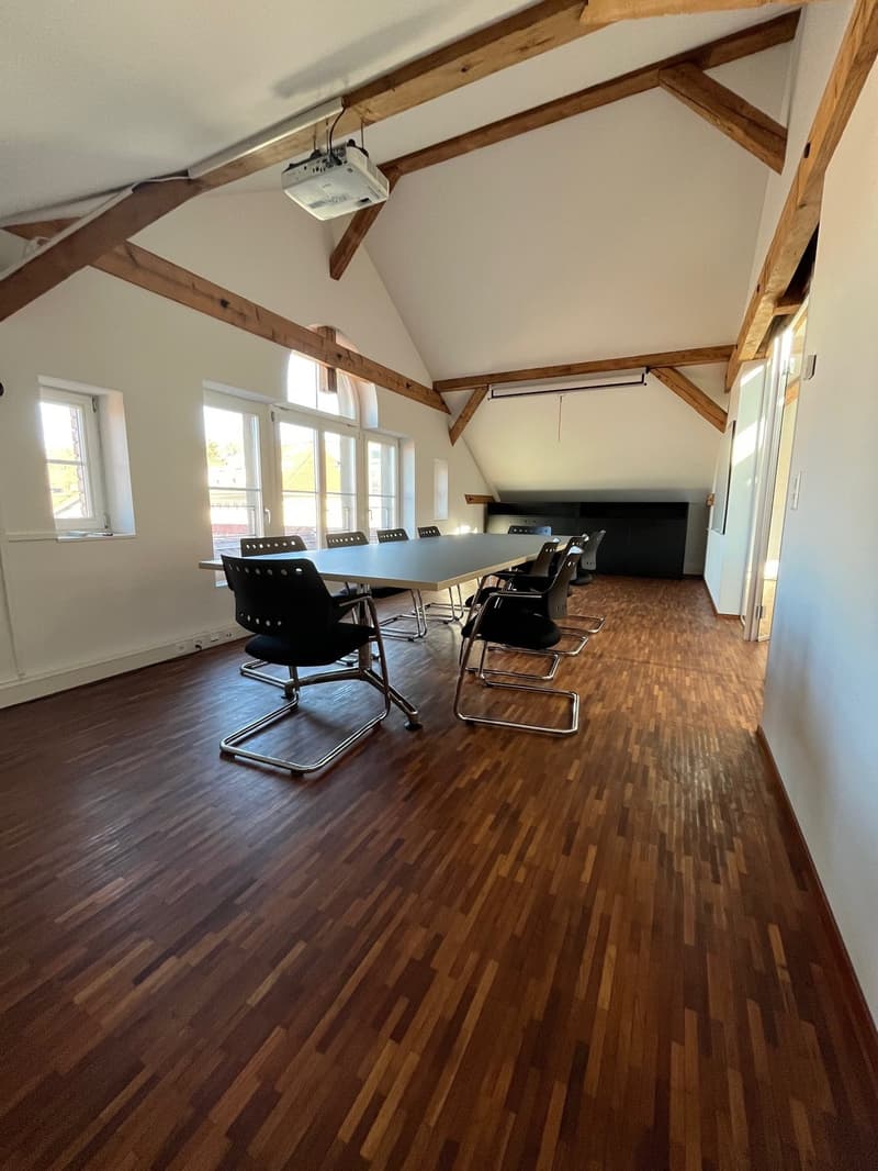 empty room, long table, chairs, projector, wooden beams, windows, wooden floor