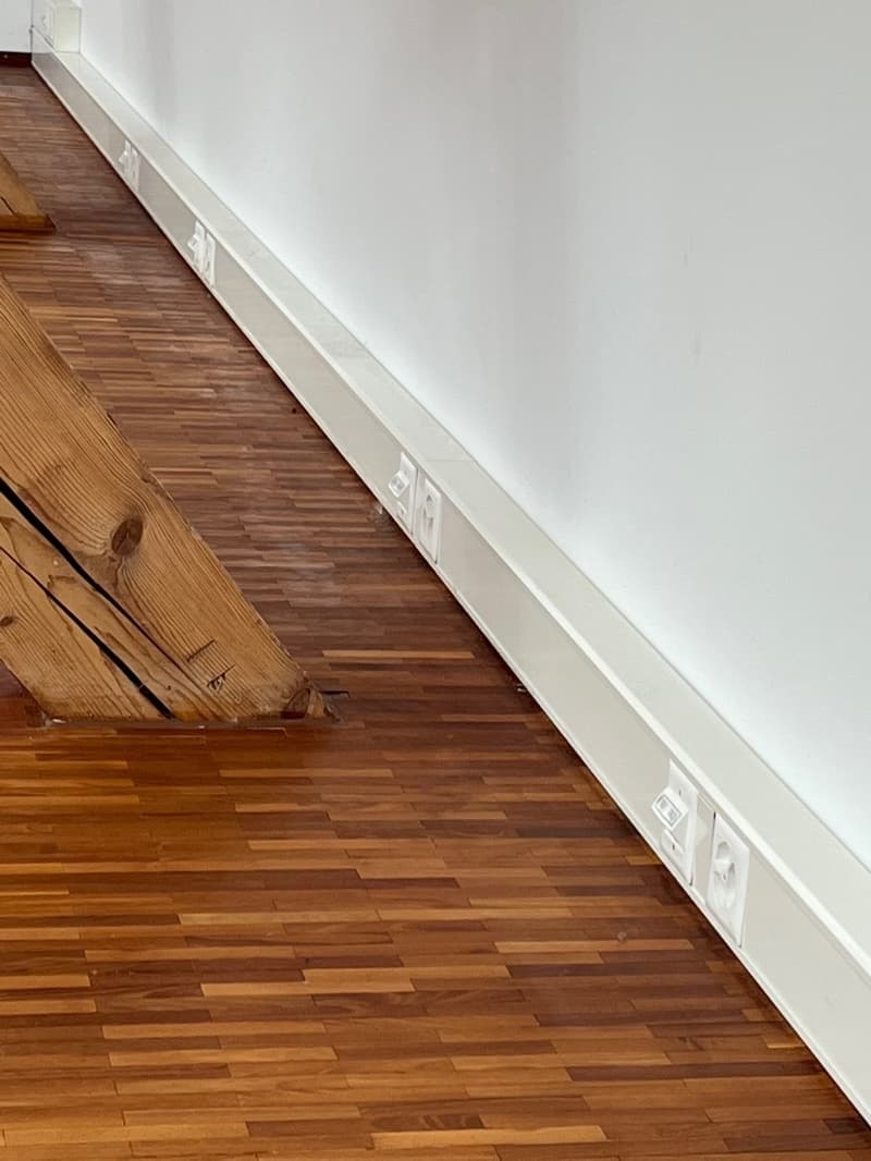 wooden floor, white wall, power outlets