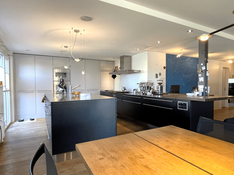 modern kitchen with black countertops, white cabinets, wooden floor, large windows, central island, modern appliances